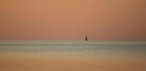 Sail boat on a peach sky.